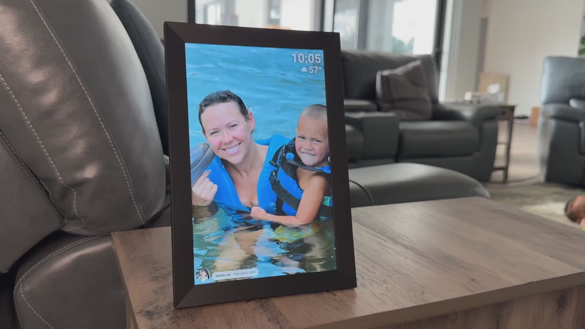 A woman is demonstrating how to send photos and videos to the UK Technology Black Digital Photo Frame and swiping through photos demonstrating the product.