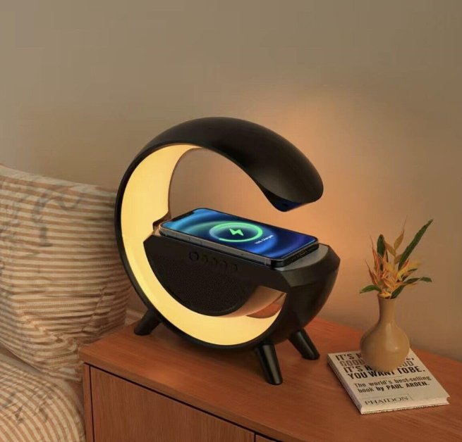 UK Technology G Lamp Wireless Charger Speaker black on a bedside table with a yellow light displayed